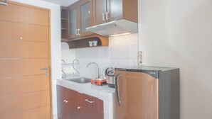 A kitchen with wooden cabinets, a stainless steel refrigerator, and a microwave. - Serene Studio Apartment At Margonda Residence 2 (Depok)
