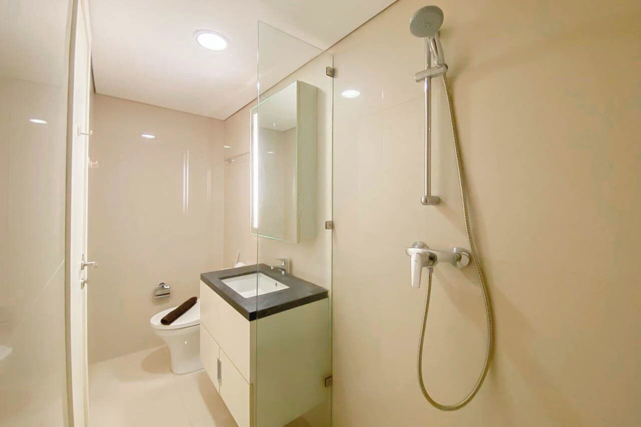 A modern bathroom with a glass shower enclosure, a toilet, and a sink with a mirror above it.