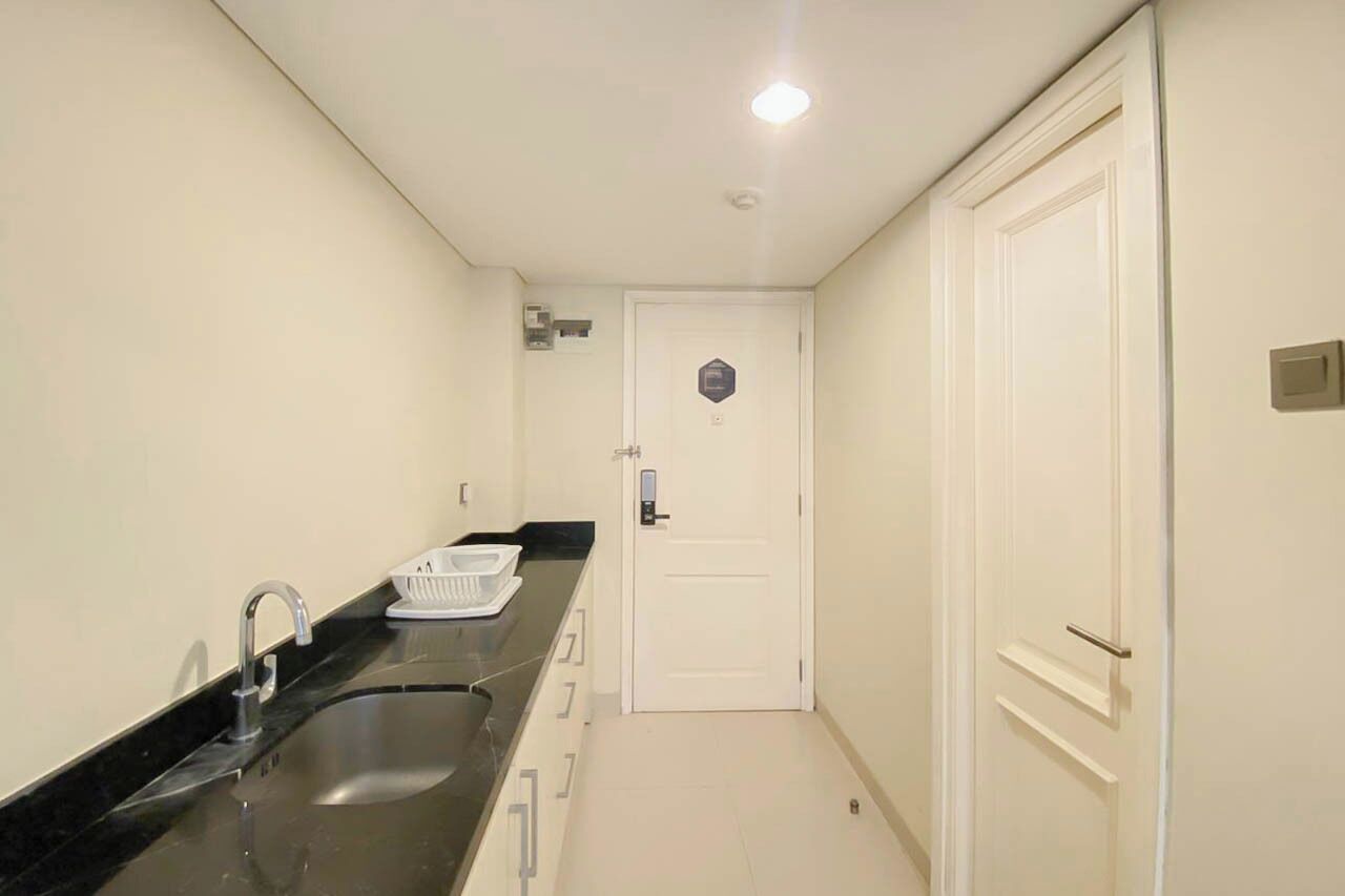A narrow kitchen with a sink, a countertop, and a door with a lock.
