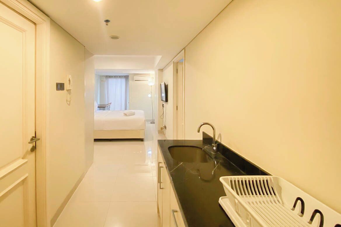 A narrow hotel corridor with a bathroom, a bed, and a sink.