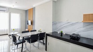 A modern kitchen with a marble backsplash, a dining area with a round table and chairs, and a built-in oven. - Clean Space And Well Located 2Br At Nifarro Park Apartment (Jakarta)