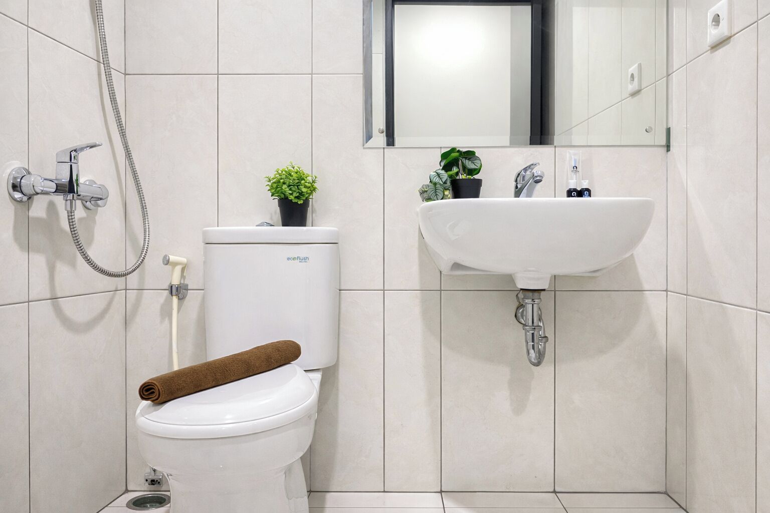 Une salle de bain équipée de toilettes, d’une douche, d’un lavabo et d’un miroir.