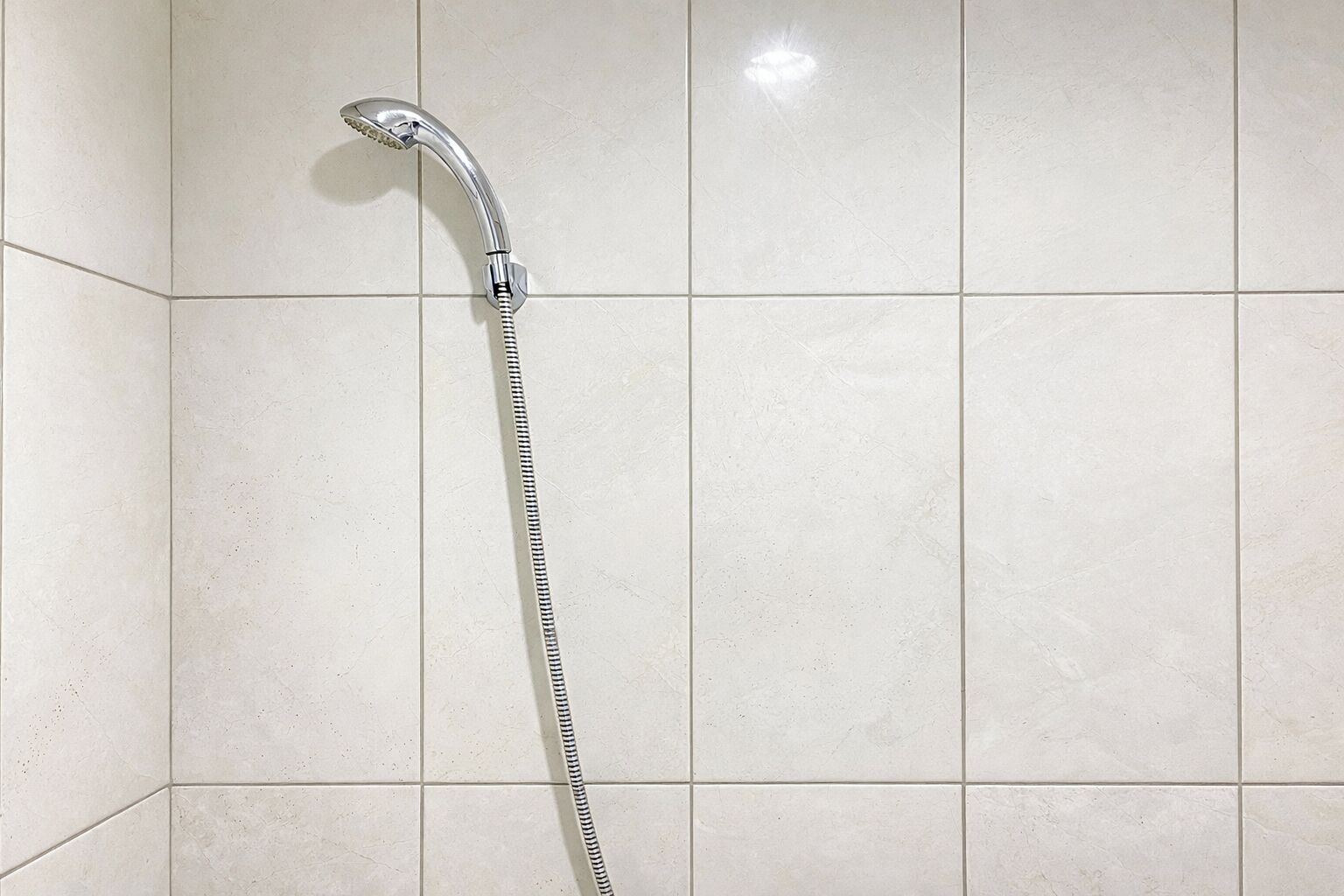Chuveiro fixado em uma parede com azulejos.