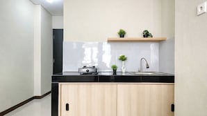 A compact kitchen with a black countertop, a built-in stove, a sink, and wooden cabinets. - Wonderful Studio At Apartment Nifarro Park Near Pasar Minggu Station (Jakarta)