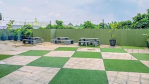 A rooftop patio with checkered flooring, outdoor seating, and string lights. - Wonderful Studio At Apartment Nifarro Park Near Pasar Minggu Station (Jakarta)