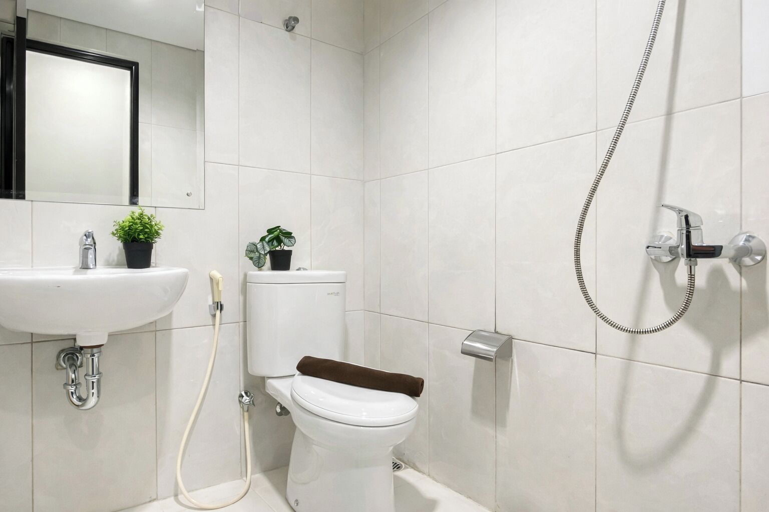 Un bagno moderno con lavandino, WC e doccia, tutti in bianco.