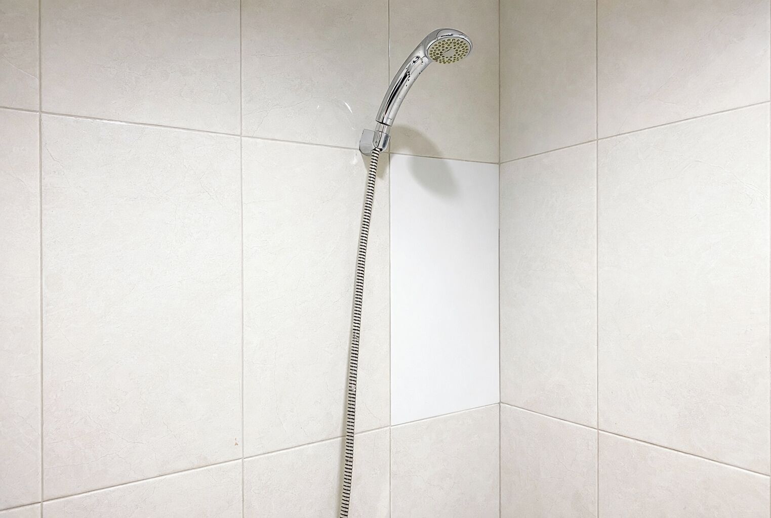 A showerhead mounted on a tiled wall.
