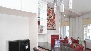 Uma sala de estar moderna com uma mesa de jantar de vidro, um sofá vermelho e um quadro decorativo.