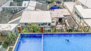 Uma piscina no terraço com água azul cristalina, cercada por edifícios residenciais.