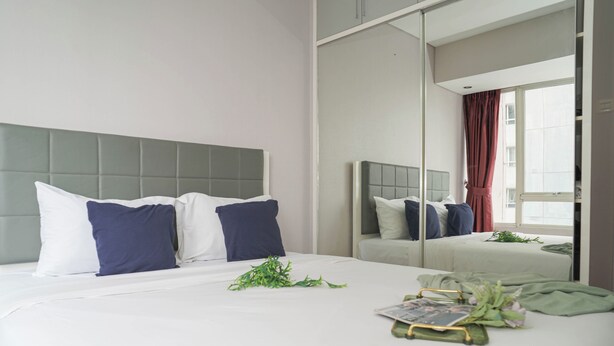 Quarto de hotel moderno com uma cama grande, um espelho e uma janela com cortinas.