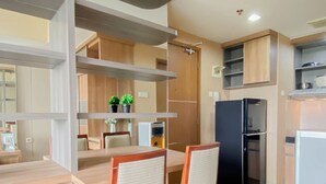 Een moderne keuken met een eethoek, houten kastjes, een zwarte koelkast en twee potplanten op het aanrecht.