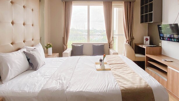 Een hotelkamer met een groot bed, een televisie, een bureau en uitzicht op de stad.