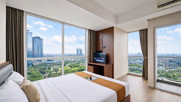 A hotel room with a large bed, a TV, and a city view. - Wooden Accents Studio For 2 Pax At Pacific Garden Campus Town Apartment (Tangerang)