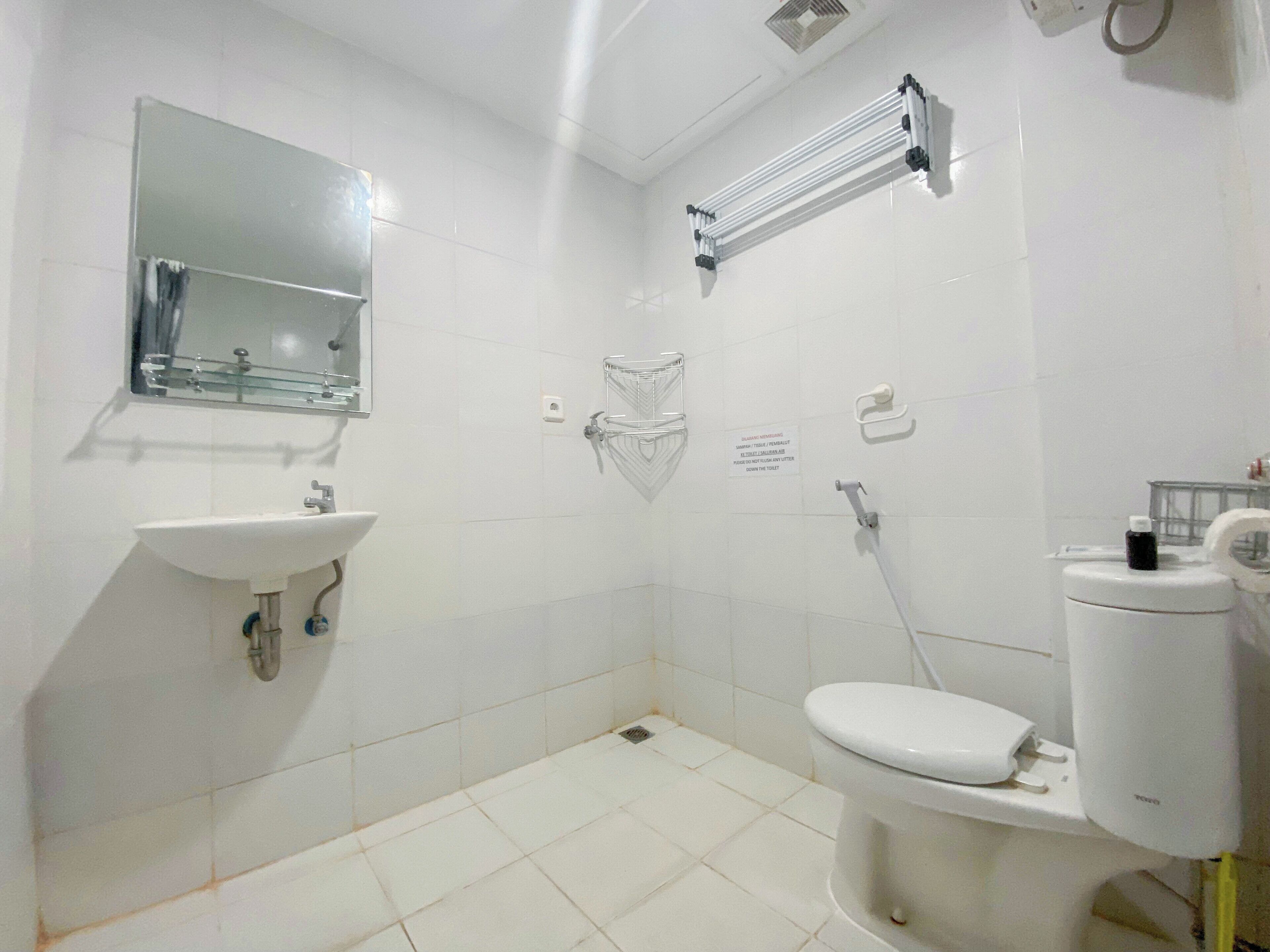 Une salle de bain avec un lavabo blanc, un miroir, des toilettes et un porte-serviettes.