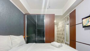 Une chambre d’hôtel comprenant un lit, une armoire, une télévision et un espace douche.