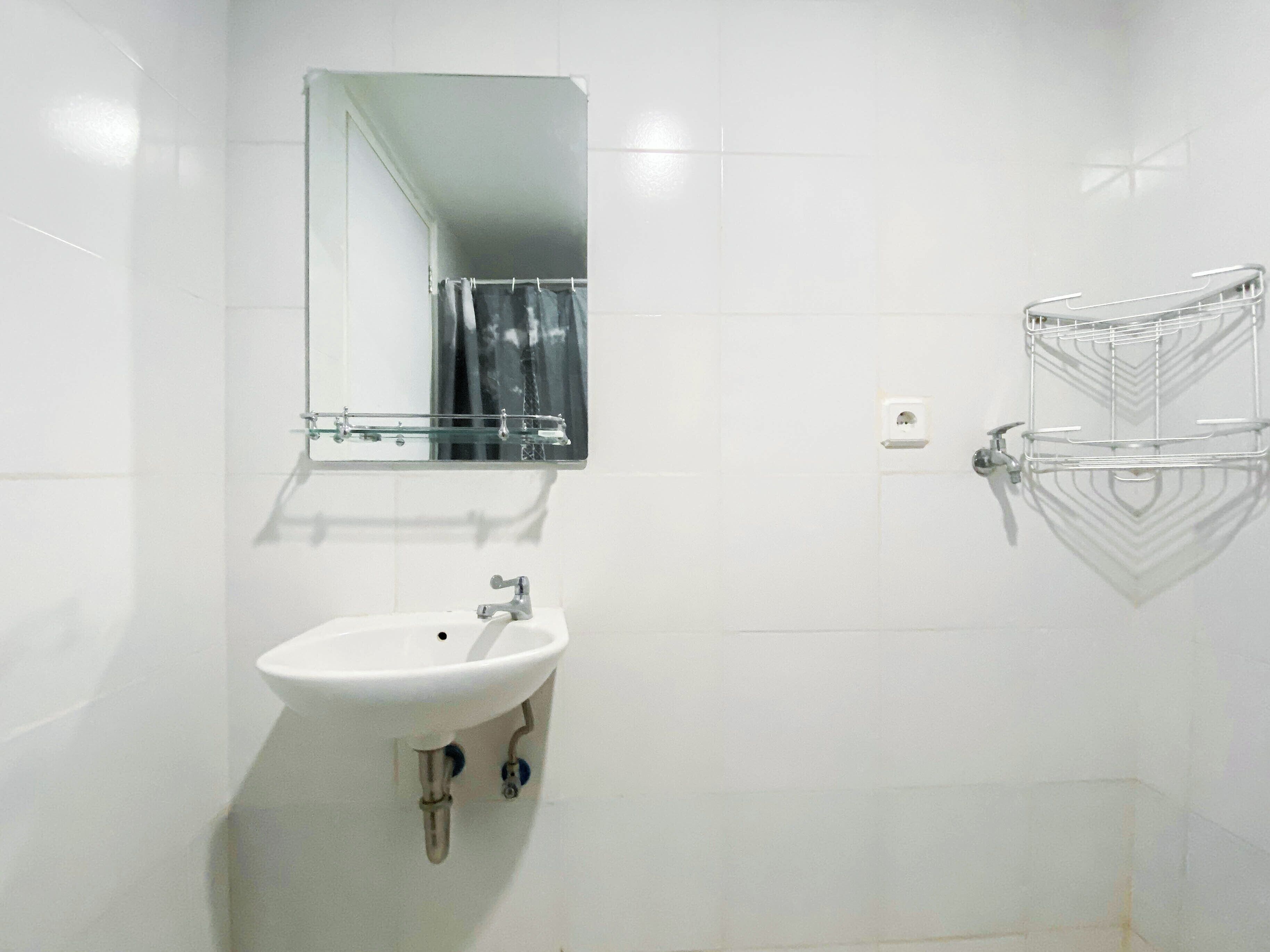 A bathroom with a white sink, a mirror, and a shower area.