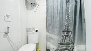 Une salle de bain équipée de toilettes, d’une douche et d’un rideau représentant la Tour Eiffel.
