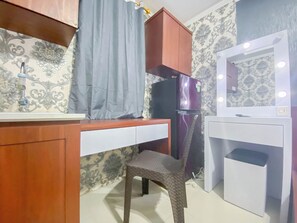 A compact kitchen with a wooden countertop, a chair, a refrigerator, and a white cabinet with a mirror. - Simply And Homey Studio (No Kitchen) Room Apartment Paltrow City (Semarang)