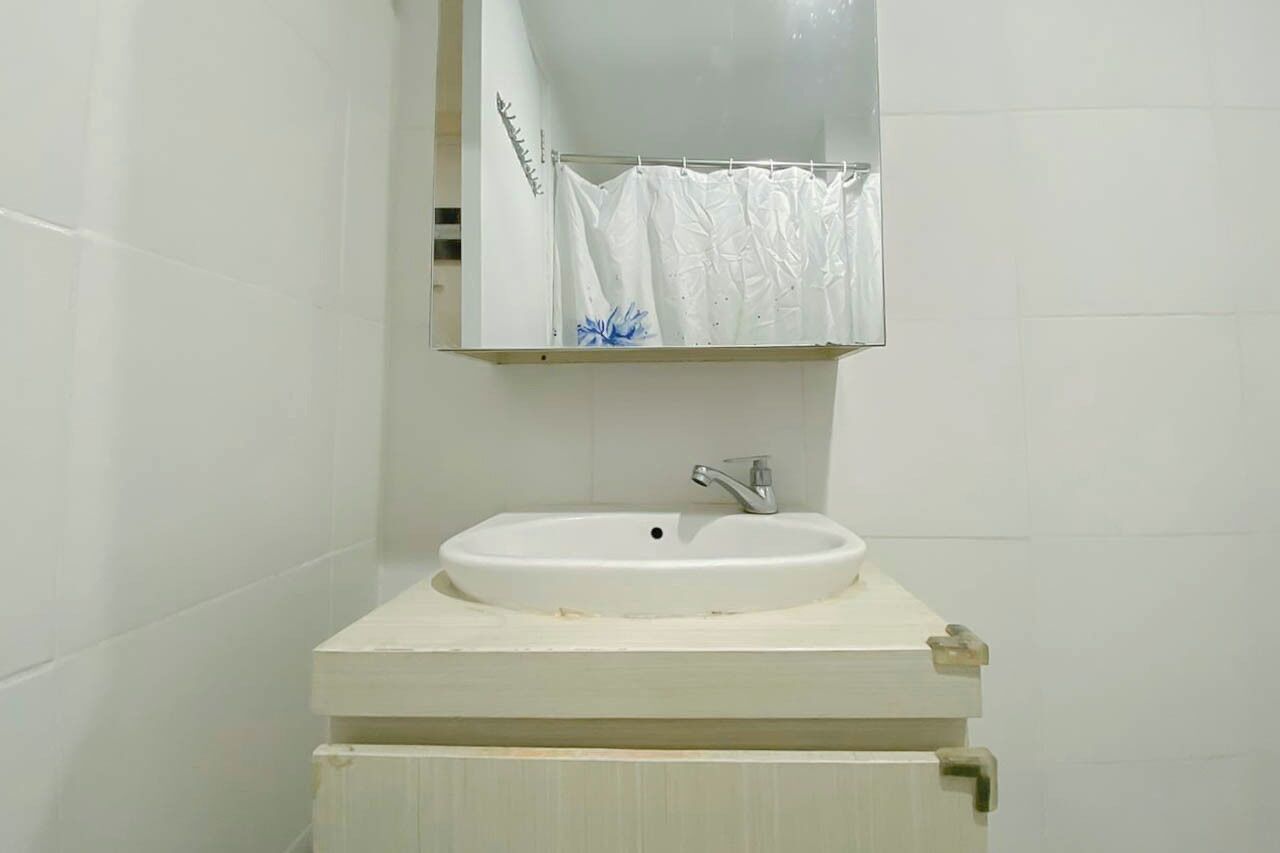 A bathroom with a white sink, a mirror above it, and a white shower curtain.