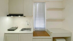 A compact kitchen with a built-in stove, a sink, and a window with blinds. - Minimalist Style Studio Near Undip At Paltrow City Apartment (Semarang)