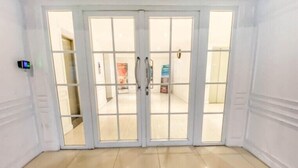 A room with a large glass door leading to an outdoor area, a small control panel on the wall, and a tiled floor. - Minimalist Style Studio Near Undip At Paltrow City Apartment (Semarang)
