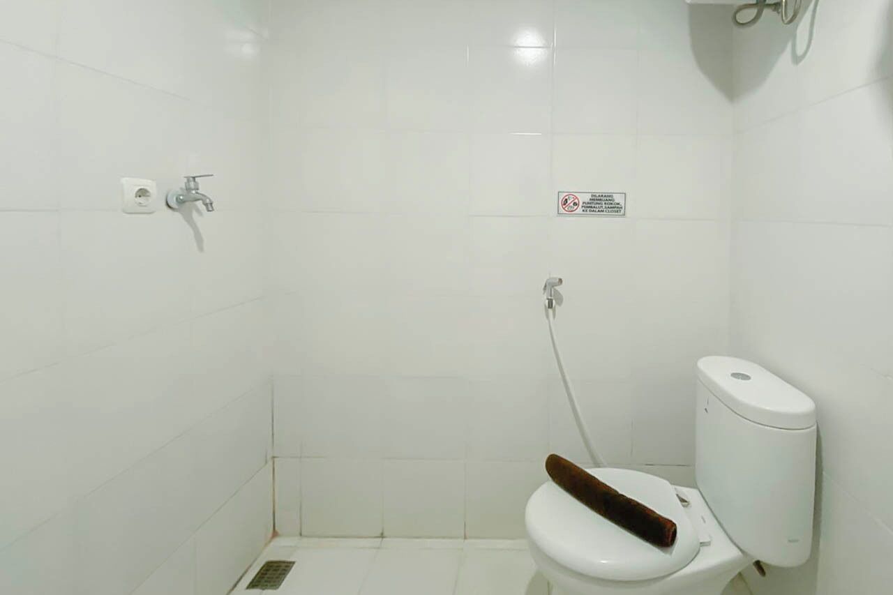 A small, white-walled bathroom with a toilet, a shower, and a hand dryer.