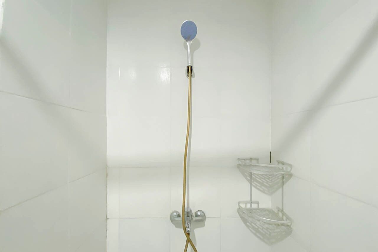 Ducha con cabezal de ducha manual, estante de vidrio y repisa metálica.