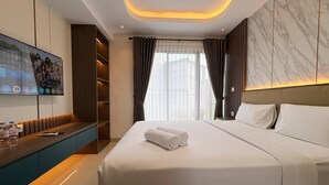 Ein modernes Hotelzimmer mit einem großen Bett, einem an der Wand montierten Fernseher, einem eingebauten Kleiderschrank und einer Wand mit Marmoroptik.