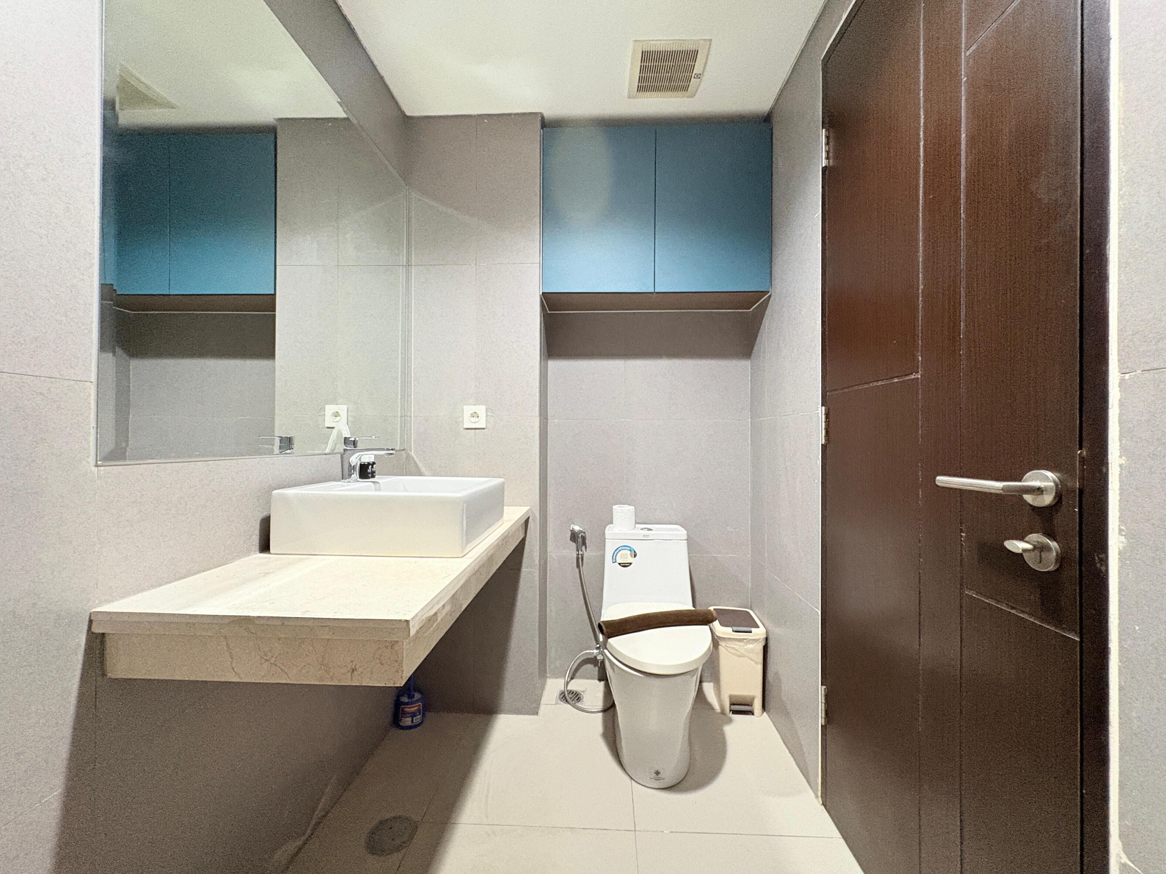 Ein Badezimmer mit Waschbecken, Spiegel, Toilette und Schrank.