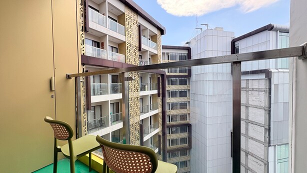 Ein Balkon mit zwei Stühlen und Blick auf die Nachbargebäude, der Himmel ist wolkenlos.