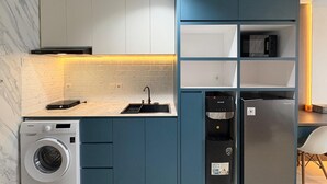 Eine kleine Küche mit Waschmaschine, integriertem Spülbecken und Kühlschrank.
