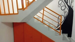 Eine Treppe mit Glasgeländer und orangefarbenen Handläufen, die zu einer unteren Ebene führt.