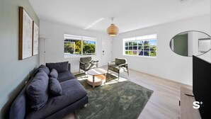 A modern living room with a sofa, chairs, a coffee table, and a TV. - Miami Retreat 1-BD - Parking and Gym (North Miami)