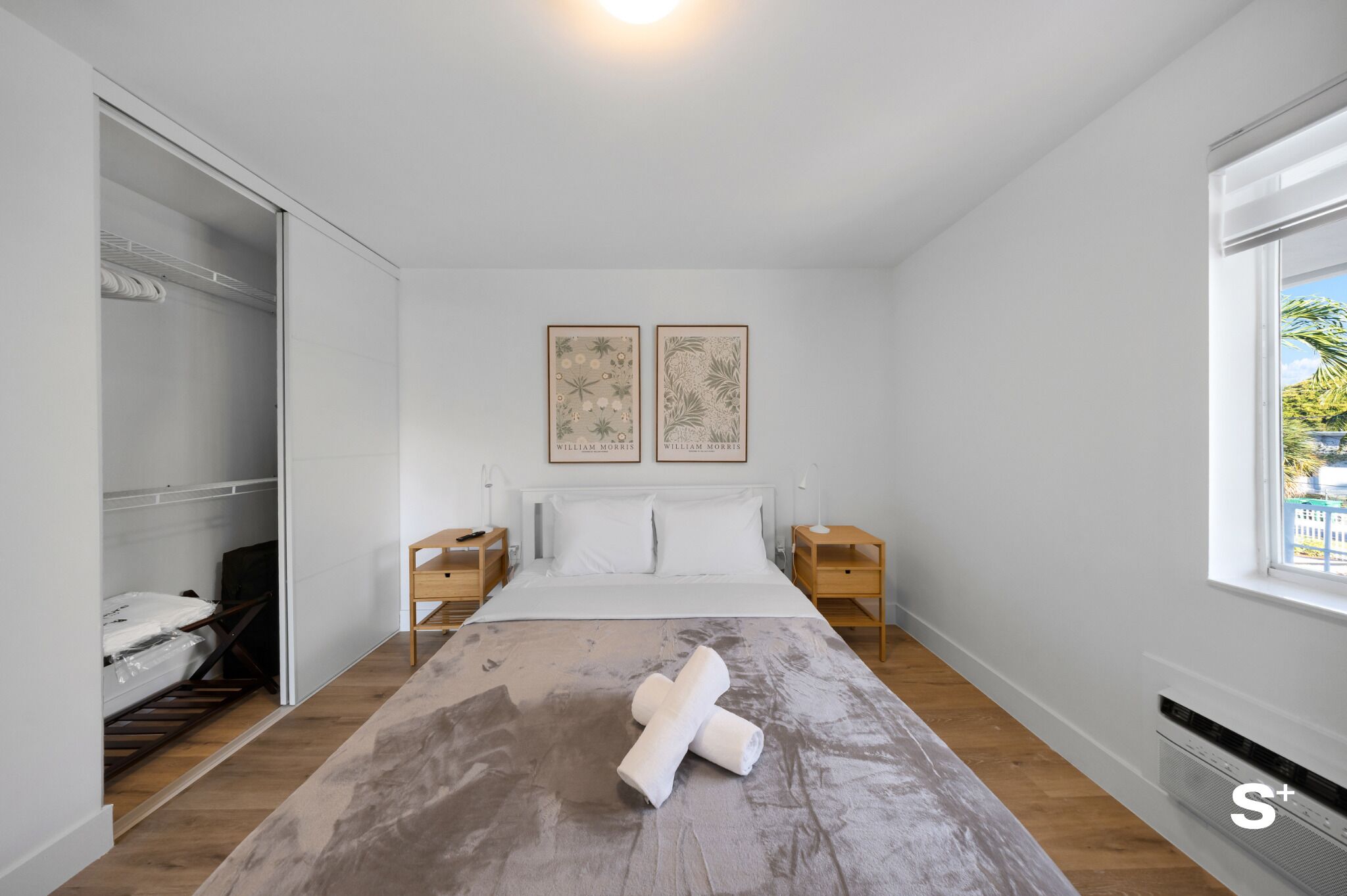 Une chambre à coucher avec un lit, deux tables de chevet, une armoire et une fenêtre donnant sur un beau paysage.