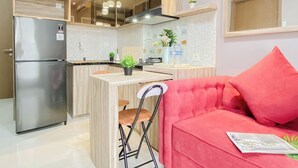 A modern kitchen with a built-in island, stainless steel refrigerator, and pendant lighting. - 2BR Corner with South and East View at Podomoro Golf View Apartment (Gunung Putri)