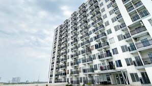 A high-rise residential building with multiple balconies, large windows, and a flat facade. - Simple Style Studio At Prima Orchard Apartment (Bekasi)