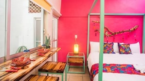 A room with a bed, a wooden table with a lamp, and a window. - Maria Casa Malecon - Only Adults (Puerto Vallarta)
