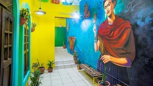 A brightly colored hallway with a mural, potted plants, and a bench. - Maria Casa Malecon - Only Adults (Puerto Vallarta)