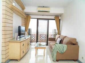 Ein Wohnzimmer mit einer Couch, einem Couchtisch, einem Fernseher und einem Balkon mit Blick.