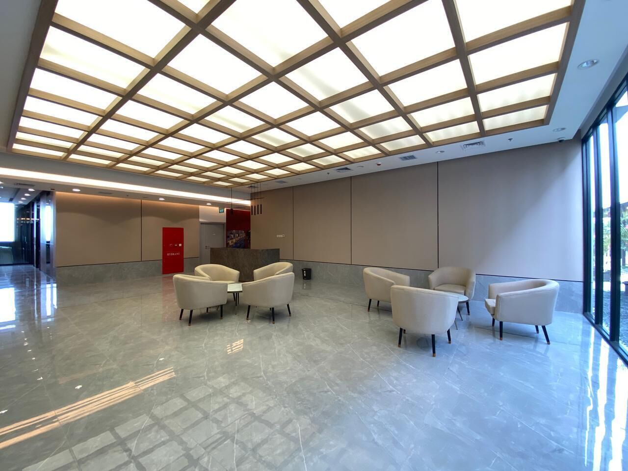 Eine geräumige Lobby mit hoher Decke, einem Empfangsbereich und einer Sitzecke.