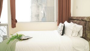 A bedroom with a bed, curtains, a window, and a plant. - Nice Look Studio Apartment At Saladdin Mansion (Depok)