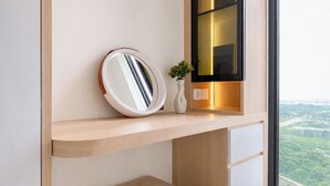 A modern bathroom with a round mirror, a small white vase with a plant, and a shelf with a book. - Modern Japandi Studio At Sayana Bekasi Apartment (Bekasi)