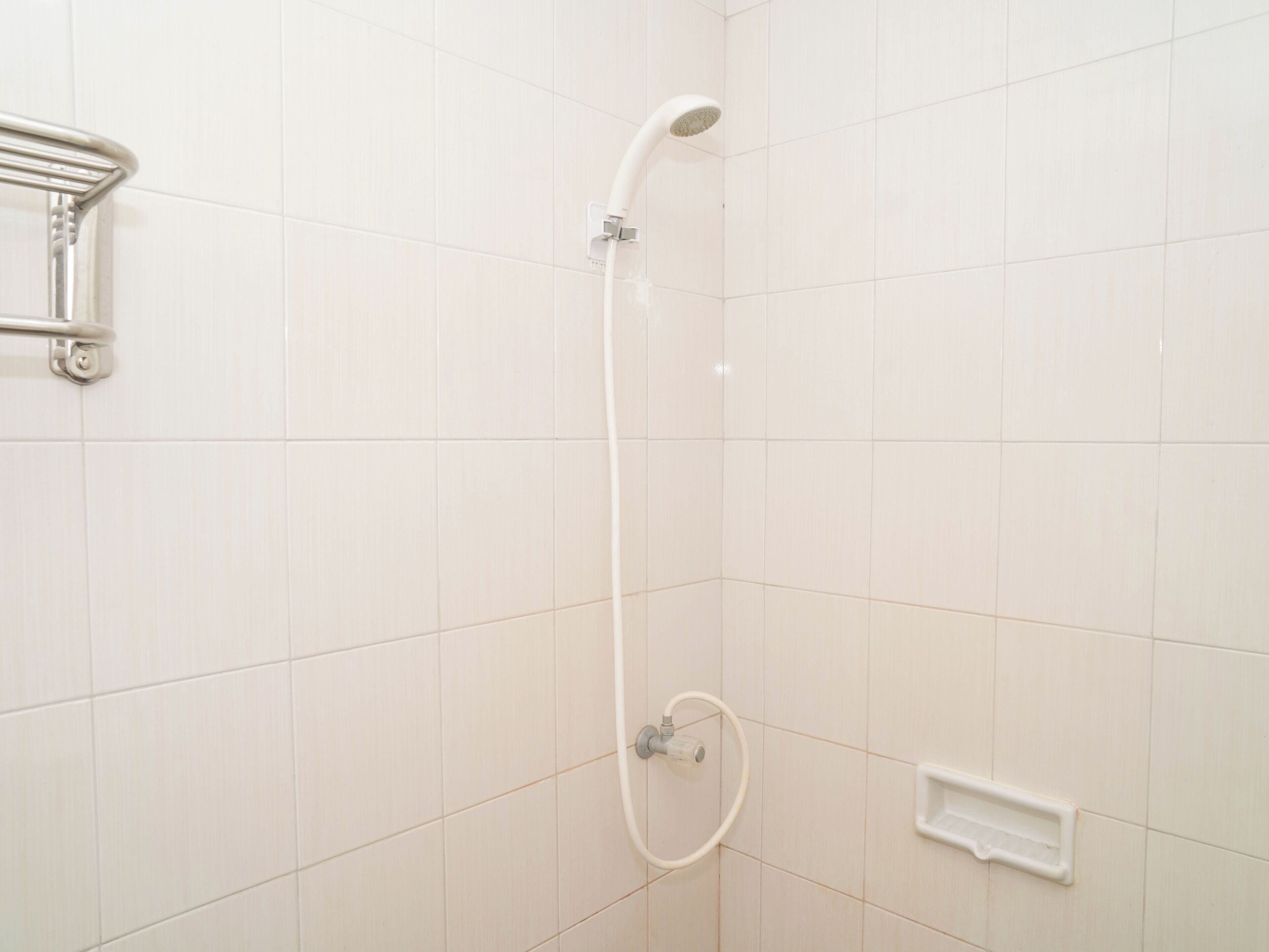 A shower with a handheld showerhead and a wall-mounted control valve.