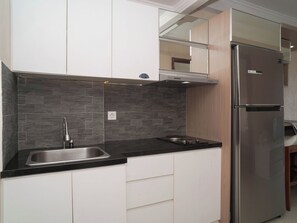 A modern kitchen with white cabinets, a stainless steel sink, and a double-door refrigerator. - Good Location 1Br At Apartment Signature Park Grande (Jakarta)