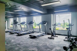 A gym with treadmills, exercise bikes, and dumbbells. - Gorgeous And Homey Studio Sky House Alam Sutera Apartment (Tangerang)