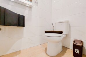 A bathroom with a toilet, a trash bin, and a wall-mounted sink. - Gorgeous And Homey Studio Sky House Alam Sutera Apartment (Tangerang)