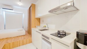 A compact kitchen with a built-in dishwasher, a stove, and a microwave. - Gorgeous And Homey Studio Sky House Alam Sutera Apartment (Tangerang)