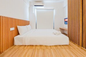 A modern hotel room with a wooden slat wall, a bed with white bedding, a flat-screen TV, and a built-in air conditioning unit. - Gorgeous And Homey Studio Sky House Alam Sutera Apartment (Tangerang)