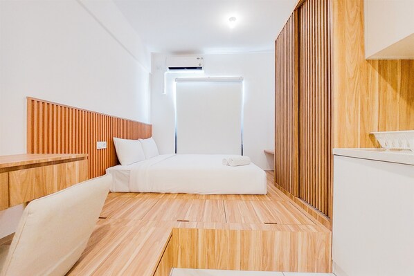 A modern hotel room with a bed, a wooden headboard, a bedside table, and a built-in wardrobe. - Gorgeous And Homey Studio Sky House Alam Sutera Apartment (Tangerang)
