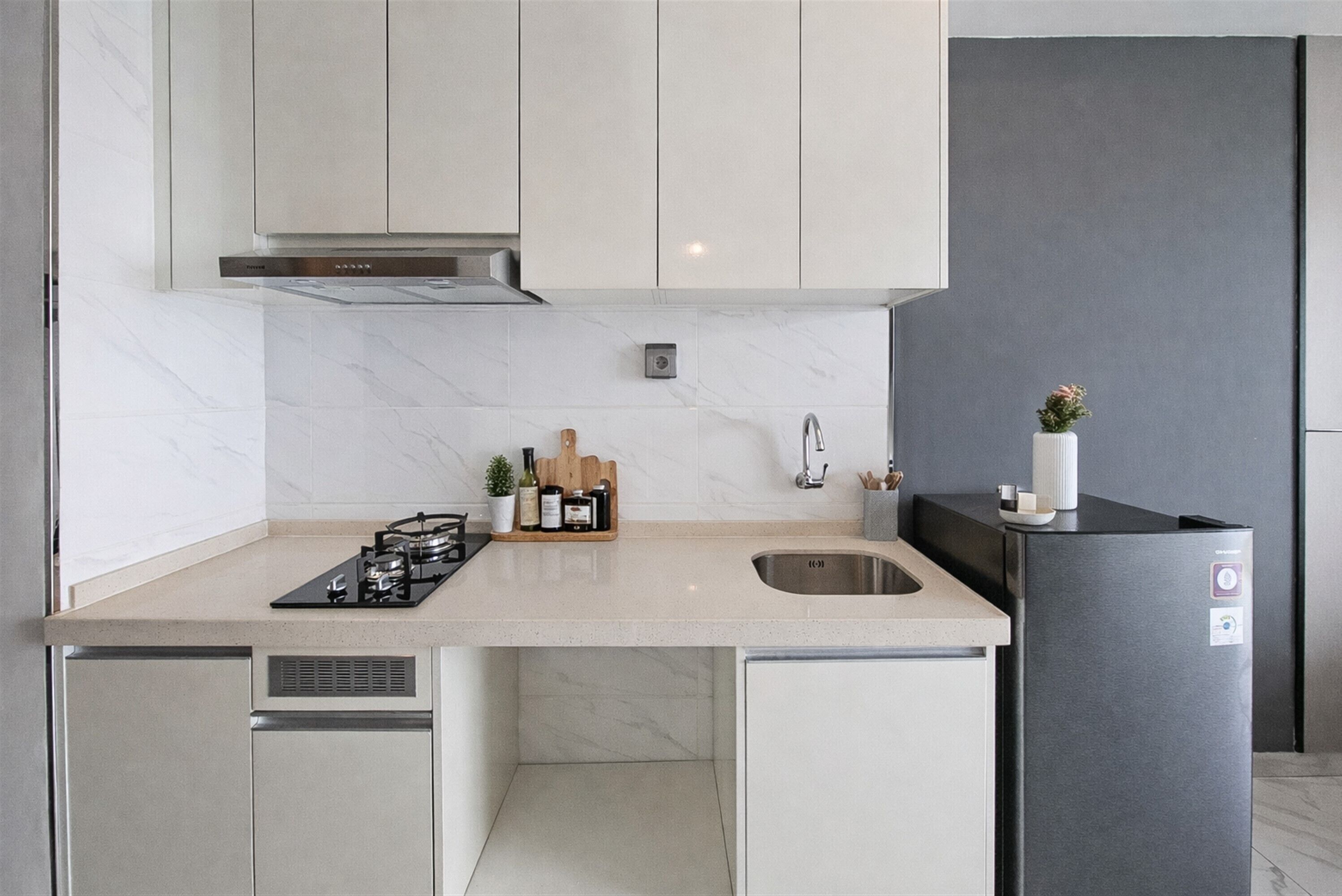 Eine moderne Küche mit Einbauherd, Spüle und einem schwarzen Kühlschrank.